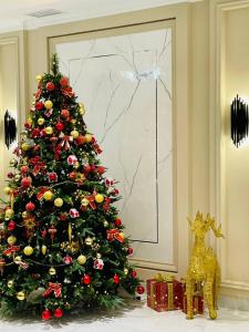 a christmas tree in a living room with a gold christmas ornament at Turon Lux Hotel in Samarkand