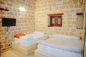 two beds in a room with a stone wall at Tebtunis in ‘Izbat an Nāmūs