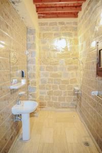 a stone bathroom with a sink and a shower at Tebtunis in ‘Izbat an Nāmūs