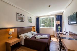 BrionにあるHotel Balneario de Compostelaのベッドとテーブルが備わるホテルルームです。