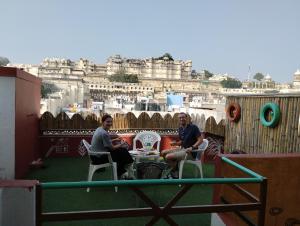 two men sitting on a balcony with a view of the city at City and Palace view guest House in Udaipur