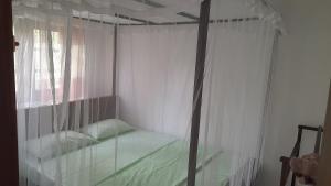 1 dormitorio con cama con dosel y ventana en Happy Haven Villa, en Weligama
