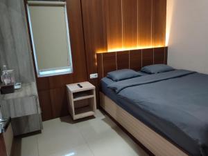 um quarto com uma cama e uma pequena mesa de cabeceira em J&L Inn Semarang em Semarang