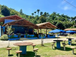 un groupe de tables et de parasols dans un parc dans l'établissement Chalé Recanto Luz Da Montanha, à Águas de Lindóia
