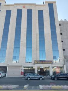 duży budynek z samochodami zaparkowanymi na parkingu w obiekcie فندق كود العربية Kud Al Arabya Apartment Hotel w mieście Chamis Muszajt