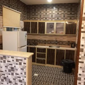 - une cuisine avec des placards en bois et un réfrigérateur blanc dans l'établissement لؤلؤ الدرب...ليالي ملكية, à Qarār