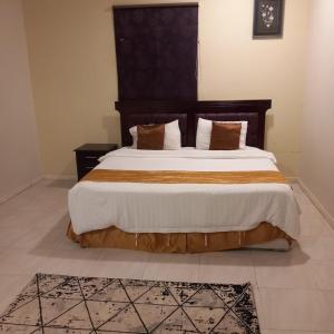 a bedroom with a large bed with a wooden headboard at لؤلؤ الدرب...ليالي ملكية in Qarār