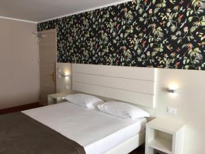 una camera da letto con un letto bianco e carta da parati floreale di Hotel Formula Int. & Puravita SPA a Rosolina