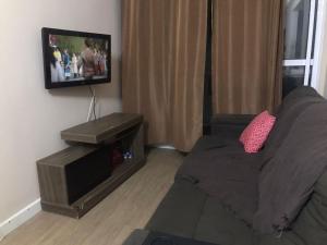 ein Wohnzimmer mit einem Sofa und einem Flachbild-TV in der Unterkunft Cabo Frio com piscina e excelente localização in Cabo Frio