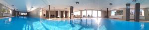a large swimming pool with blue water in a building at Gerlitzen-Apartments in Kanzelhöhe