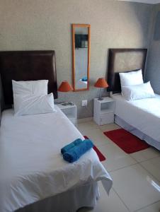 a bedroom with two beds and two lamps and a mirror at Ngena guesthouse in Cape Town +14 photos