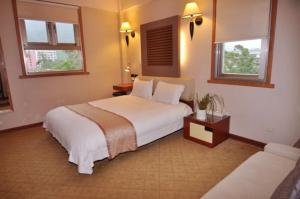 a bedroom with a large white bed and two windows at Tian Long Hotel in Jiaoxi