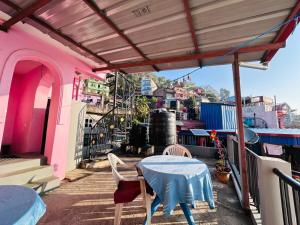 una mesa y sillas en el balcón de un edificio rosa en City View Home Stay en Tānsen