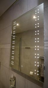 a mirror in a bathroom with lights on it at The Rose Bed and Breakfast in Stainland