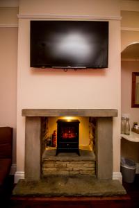 a fireplace with a flat screen tv on the wall at The Rose Bed and Breakfast in Stainland