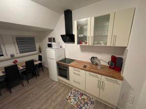 cocina con armarios blancos y mesa con microondas en Ferienwohnung, Monteurwohnung, Unterkunft in Warstein NRW, Deutschland en Warstein