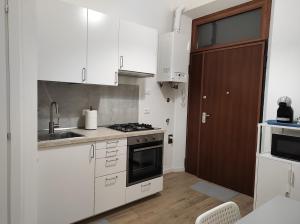 una cocina con armarios blancos y fregadero en KAIROS RESIDENCE en Parma