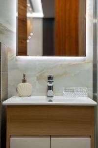 Mans lux 8 Apartman في زلاتيبور: حوض الحمام مع مرآة وموزع الصابون