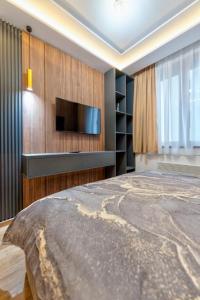 Mans lux 8 Apartman في زلاتيبور: غرفة نوم مع تلفزيون بشاشة مسطحة وسرير