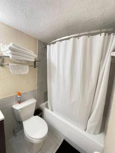 a bathroom with a toilet and a white shower curtain at Charming seaside studio for 4 people! - Rate included resort fee-Parking fee not included- in Sunny Isles Beach