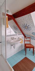 a bathroom with a sink and a chair at Hotel garni Lindenhof im Steigerwald in Oberaurach