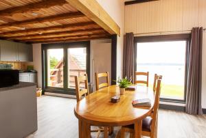 a dining room with a wooden table and a kitchen at Doune Bay Lodge 