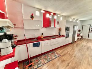 uma grande cozinha com armários brancos e detalhes vermelhos em Beachfront - ocean view - sea view - modern - cozy - Netflix & Wi-Fi - islet view - dunes view - mountain view em Telde