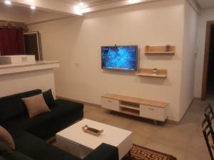 a living room with a couch and a tv on the wall at apparemment luxe cité wahat in Le Kram