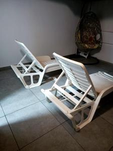 2 chaises longues blanches assises sur un sol carrelé dans l'établissement Fuerte Vibes Guest House In Corralejo, à Corralejo