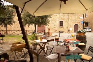un patio con mesas, sillas y una sombrilla en La Ripa Del Drago en Bibbona