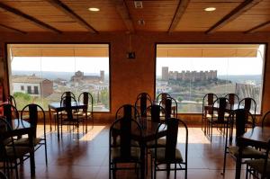 ein Esszimmer mit Tischen, Stühlen und Fenstern in der Unterkunft Hotel Restaurante Baños in Baños de la Encina