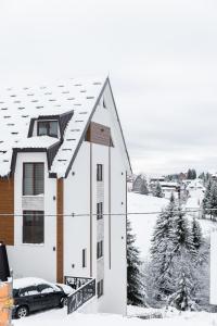 a house covered in snow with a car parked in front at Glečer Kop, Cozy design apartment A5 in Kopaonik