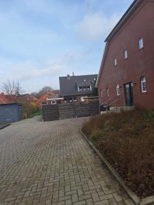 a brick driveway next to a red brick building at Apartment Annies Deichliebe in Krummhörn