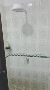 y baño con ducha y paredes de azulejos blancos. en habitacion privada en Jardin cerca al parque, en Jardín