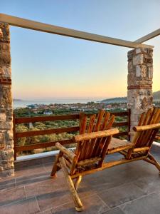 2 Holzstühle auf einem Balkon mit Aussicht in der Unterkunft Helicon Luxury Villas in Limenas