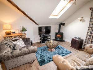 a living room with a couch and a wood stove at Peony Cottage in Ulverston