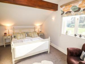 a bedroom with a white bed and a window at Peony Cottage in Ulverston