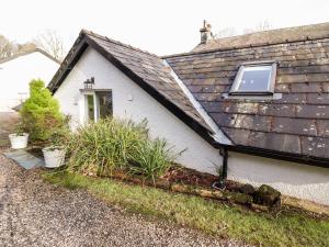 a small white house with a window and plants at Peony Cottage in Ulverston
