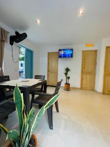 a dining room with a table and chairs and a tv at Cabaña Villa Jardín - Aldea Doradal - Santorini Colombiano in Doradal