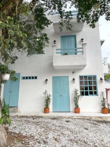 ein weißes Haus mit blauen Türen und Topfpflanzen in der Unterkunft Cabaña Villa Jardín - Aldea Doradal - Santorini Colombiano in Doradal