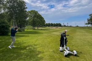 Un hombre parado junto a un carrito de golf en un campo. en Amsterdam Farmland, en Ámsterdam