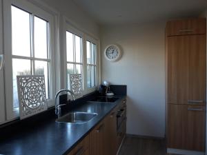 a kitchen with a sink and a clock on the wall at Strandhuis De Bakkeete B in Kamperland
