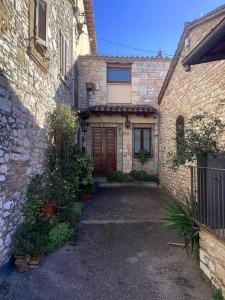 ein altes Backsteingebäude mit einer Tür im Innenhof in der Unterkunft Casa Balani in Assisi