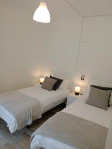 two beds in a room with two lamps at Casa Carlota in Hermigua