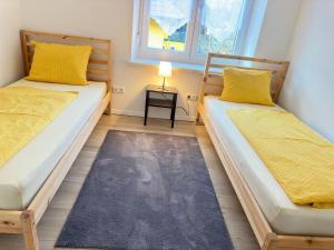 2 Betten in einem kleinen Zimmer mit gelben Kissen in der Unterkunft Appartement Niederthalheim 
