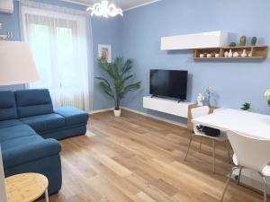ein Wohnzimmer mit einem blauen Sofa und einem TV in der Unterkunft Amalphia Home in Salerno