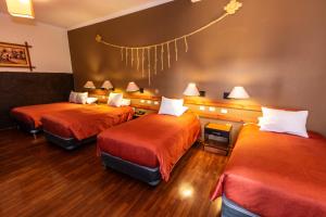 Habitación de hotel con 2 camas con sábanas de color naranja en La Casona de Rimacpampa, en Cusco