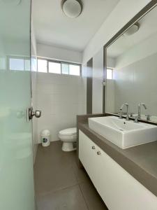 a white bathroom with a sink and a toilet at Condominio Nuevo Paracas - Sotavento in Paracas