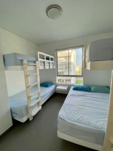 a bedroom with two bunk beds and a window at Condominio Nuevo Paracas - Sotavento in Paracas