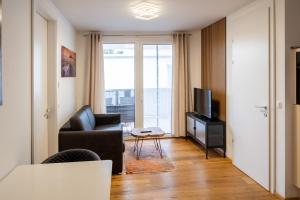 ein Wohnzimmer mit einem Sofa und einem TV in der Unterkunft Modern apartment w/ cozy balcony near city center in Wien